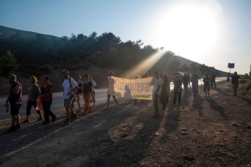 Protesters against the Kirzali gold mine march along a road. They are holding banners