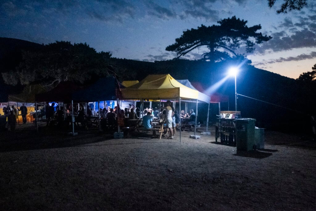 Protest camp at the Kirazli gold mine. People sitting at long tables. Dusk,